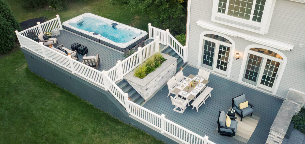 Swim spa in a backyard with a deck built around it.