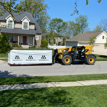 A forklift moving a swim spa that is wrapped in its shipping packaging.