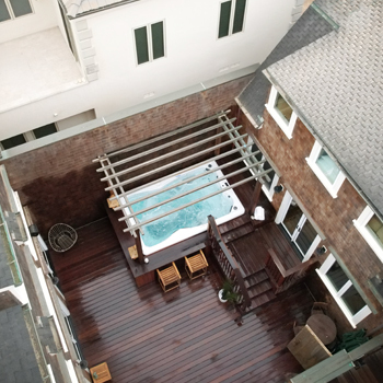 A swim spa in a small, fenced-in backyard patio.